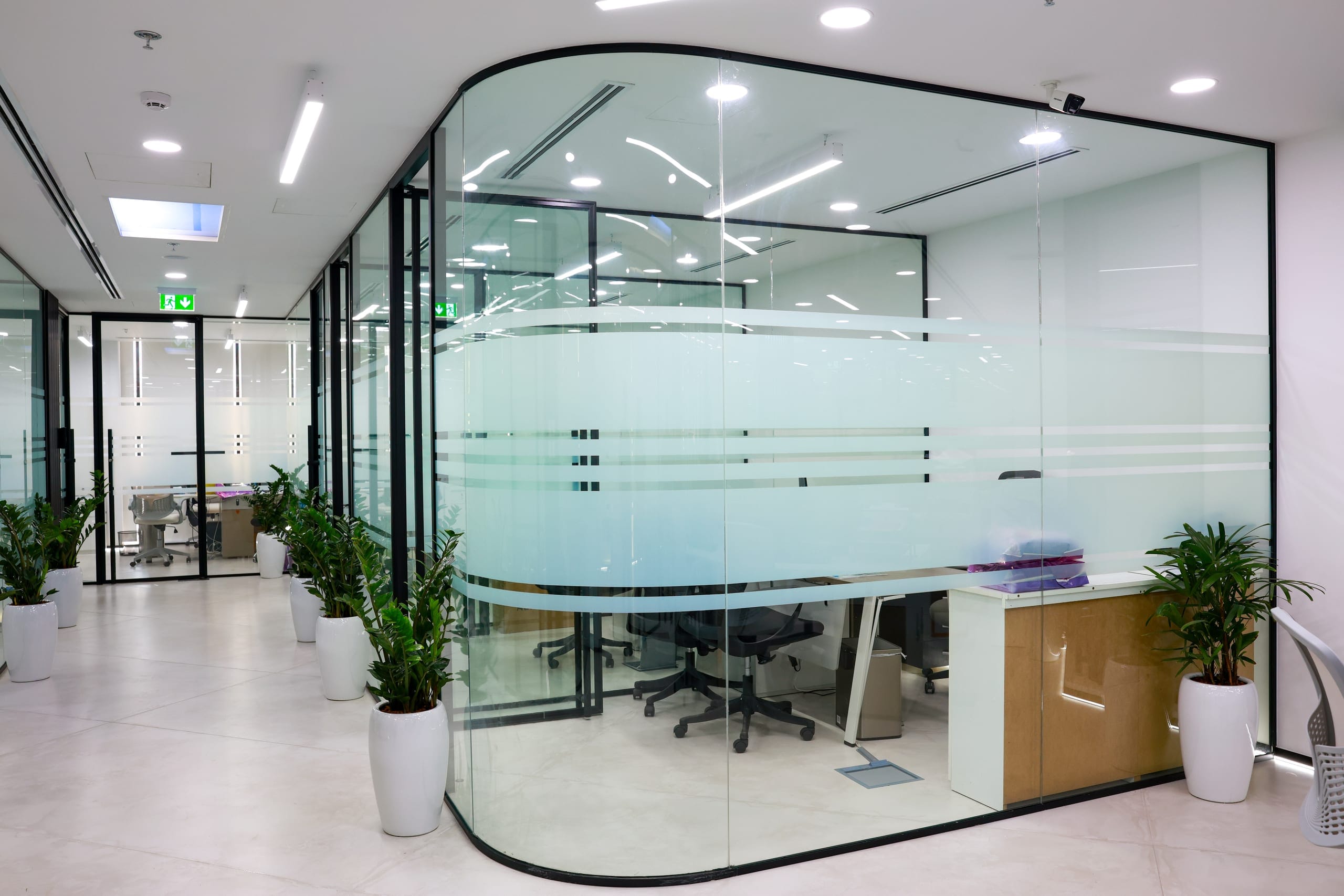 A curved glazed meeting room set into an open office floor
