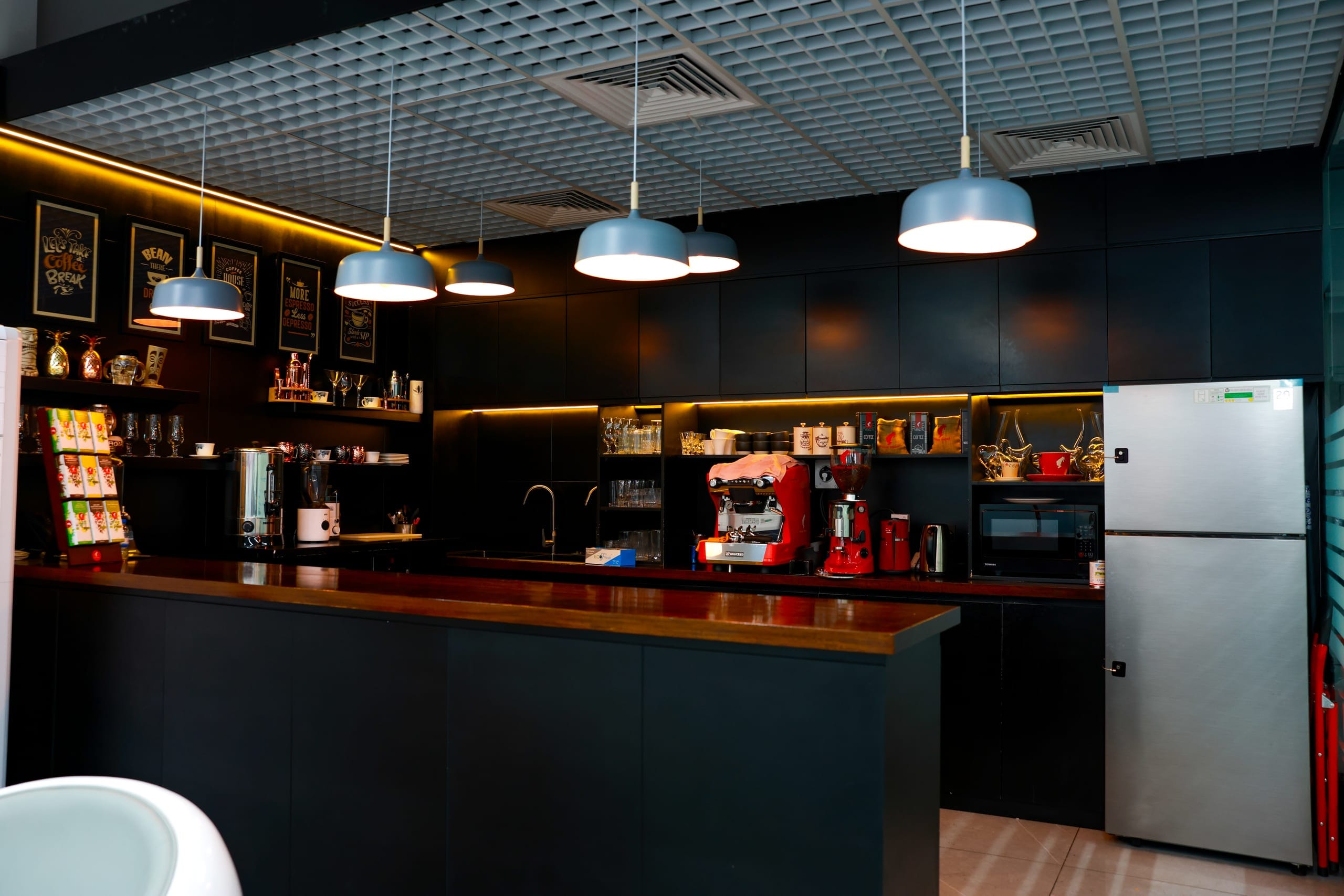A staff pantry with dark joinery and pendant lighting