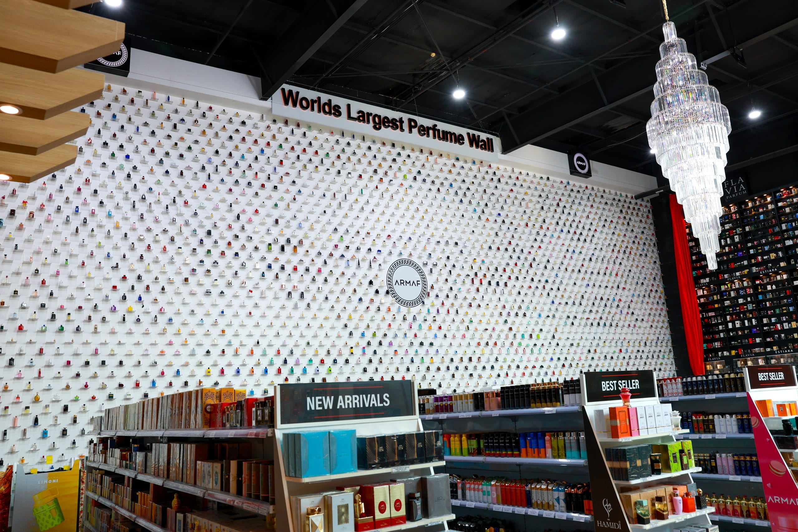 A full-height perfume display wall running the length of a retail floor
